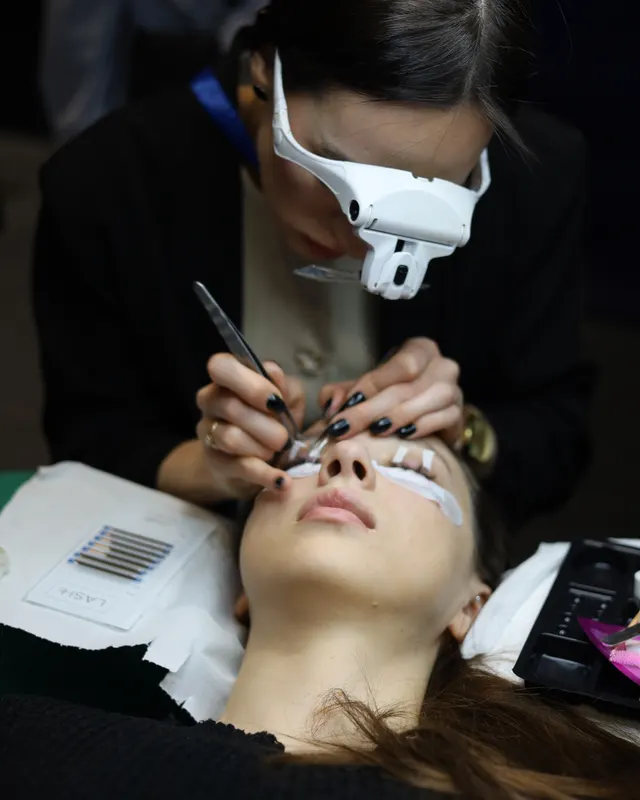 Weronika Kubaszewska stylizuje rzęsy modelce podczas wydarzenia branżowego